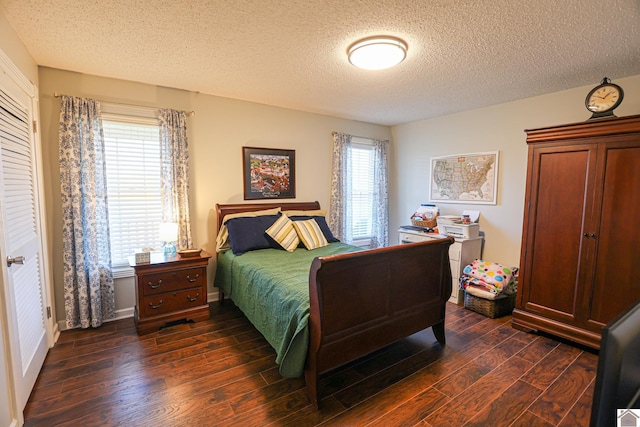 bedroom featuring multiple windows, dark wood-type flooring, and a textured ceiling