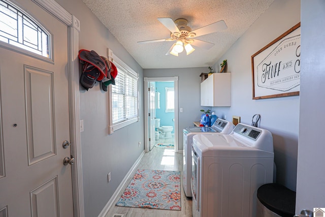 clothes washing area with washing machine and clothes dryer, baseboards, ceiling fan, cabinet space, and a textured ceiling