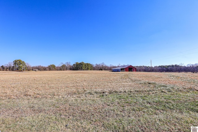 view of yard featuring an outdoor structure, a rural view, and a pole building