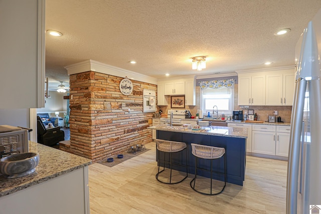 kitchen featuring light stone counters, backsplash, and white cabinets