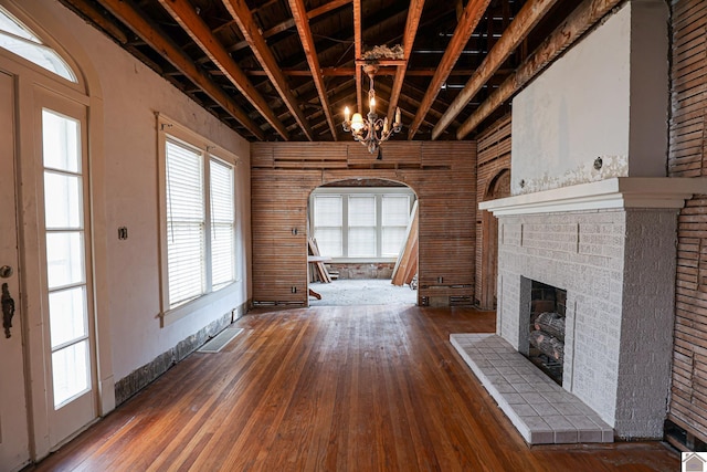 unfurnished living room with an inviting chandelier, a fireplace, and hardwood / wood-style flooring