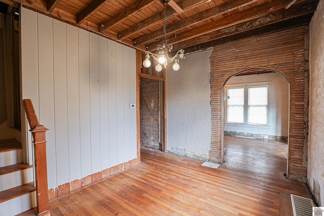 spare room with an inviting chandelier, hardwood / wood-style floors, wooden ceiling, and beam ceiling