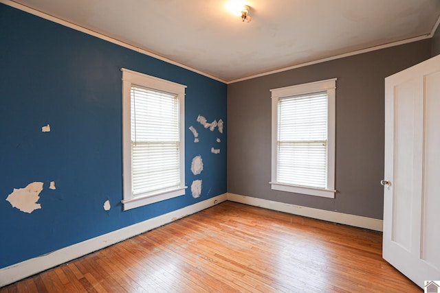 spare room featuring ornamental molding, light hardwood / wood-style flooring, and plenty of natural light