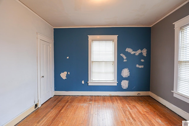 empty room with hardwood / wood-style flooring and ornamental molding