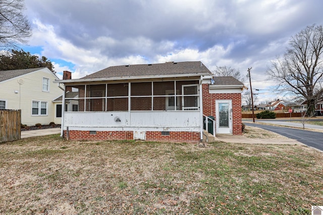 rear view of property featuring a sunroom and a lawn