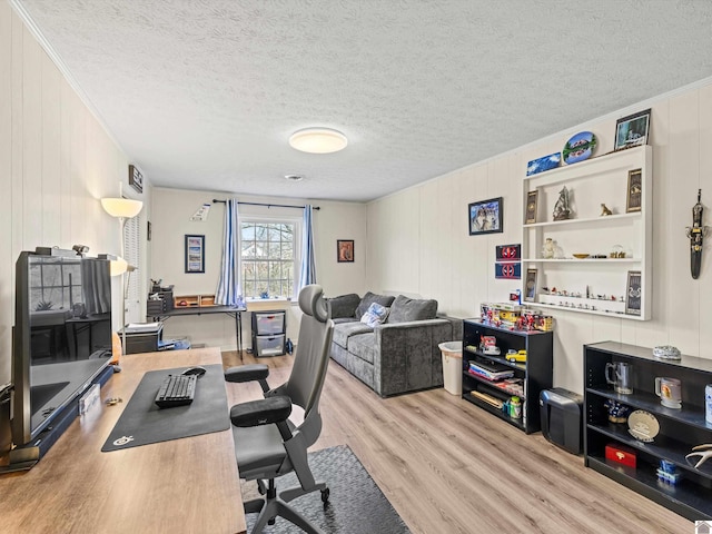 home office featuring wood walls, ornamental molding, a textured ceiling, and light wood-type flooring