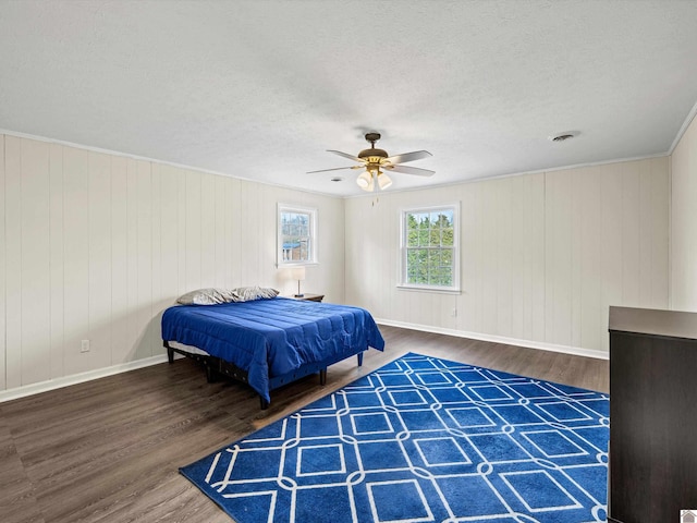 bedroom with dark hardwood / wood-style flooring, crown molding, a textured ceiling, and ceiling fan