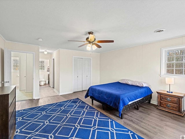 bedroom featuring ensuite bathroom, wood-type flooring, a textured ceiling, a closet, and ceiling fan