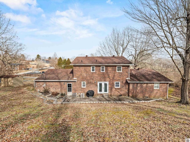 rear view of property with a lawn, central AC unit, and a patio area