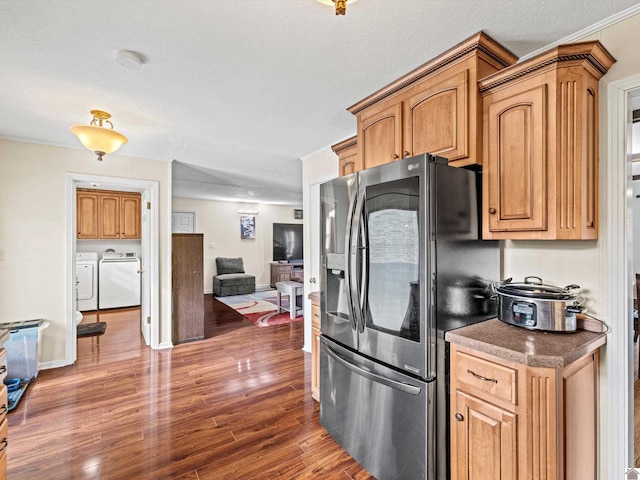 kitchen featuring a textured ceiling, stainless steel fridge, dark hardwood / wood-style floors, and washing machine and clothes dryer