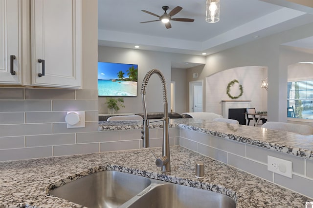 kitchen featuring tasteful backsplash, sink, light stone countertops, and ceiling fan