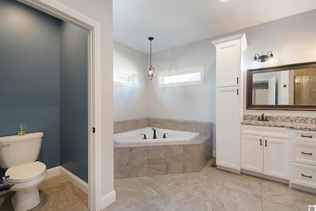 bathroom with a relaxing tiled tub, vanity, and toilet