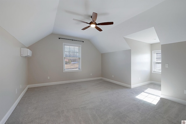 additional living space featuring a wealth of natural light, lofted ceiling, a wall mounted AC, and light colored carpet