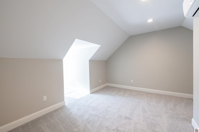 additional living space with vaulted ceiling, light colored carpet, and a wall mounted AC