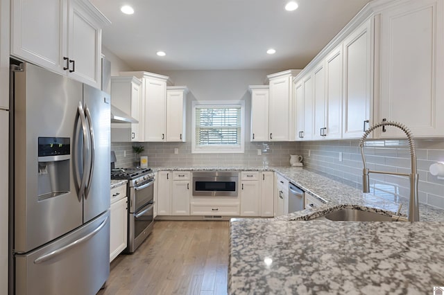 kitchen with white cabinetry, appliances with stainless steel finishes, sink, and light stone counters