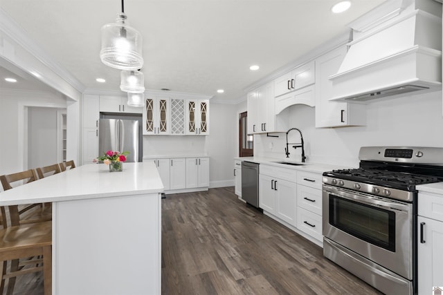 kitchen with sink, premium range hood, white cabinetry, appliances with stainless steel finishes, and a kitchen breakfast bar