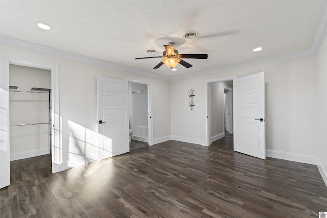 unfurnished bedroom with crown molding, dark wood-type flooring, ceiling fan, a spacious closet, and a closet