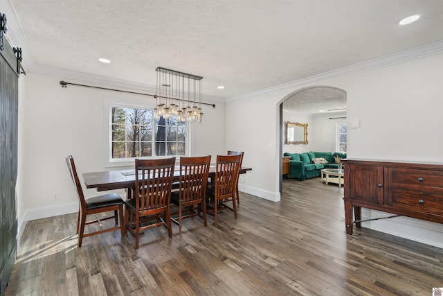 dining area featuring crown molding, a barn door, dark hardwood / wood-style floors, and a textured ceiling