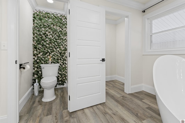 bathroom featuring ornamental molding, wood-type flooring, toilet, and a bathing tub