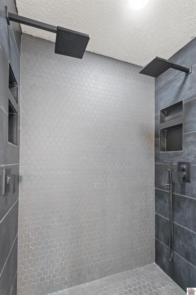 bathroom with a tile shower and a textured ceiling