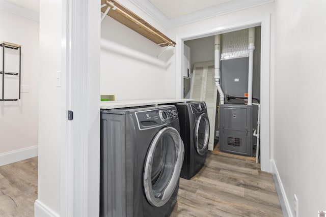 clothes washing area featuring crown molding, light wood-type flooring, and independent washer and dryer