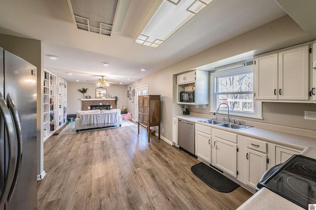 kitchen featuring sink, light hardwood / wood-style flooring, ceiling fan, appliances with stainless steel finishes, and white cabinetry