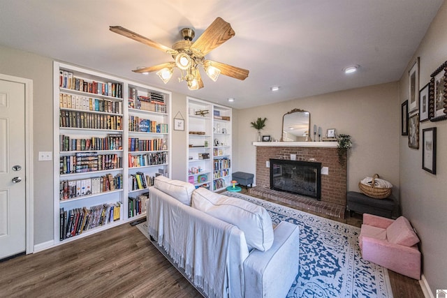 living room featuring ceiling fan, dark hardwood / wood-style floors, a brick fireplace, and built in features