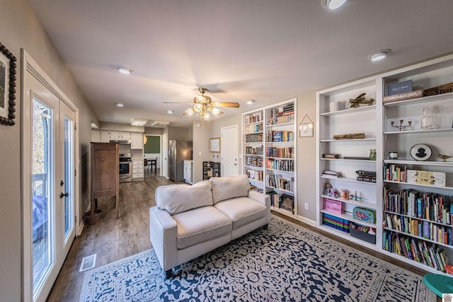 living room with dark wood-type flooring and ceiling fan