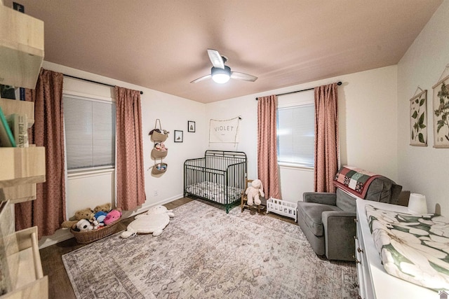 bedroom with hardwood / wood-style flooring, ceiling fan, and a crib