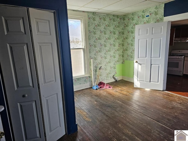 unfurnished bedroom with a drop ceiling and dark wood-type flooring