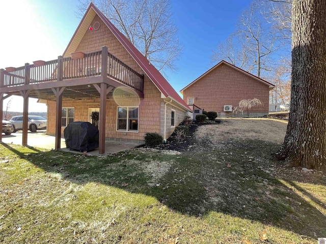 view of property exterior featuring a wooden deck, a yard, and a patio