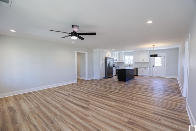 unfurnished living room with ceiling fan, sink, and light hardwood / wood-style floors