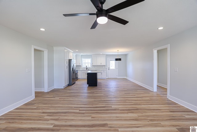 unfurnished living room featuring ceiling fan, sink, and light hardwood / wood-style flooring