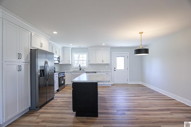 kitchen featuring a kitchen island, decorative light fixtures, white cabinetry, sink, and stainless steel appliances