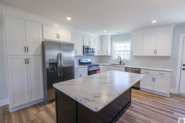 kitchen featuring sink, light hardwood / wood-style flooring, stainless steel appliances, a center island, and white cabinets