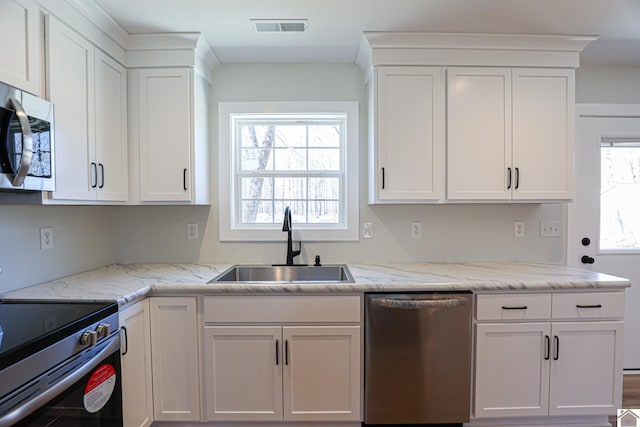 kitchen with stainless steel appliances, sink, a wealth of natural light, and white cabinets