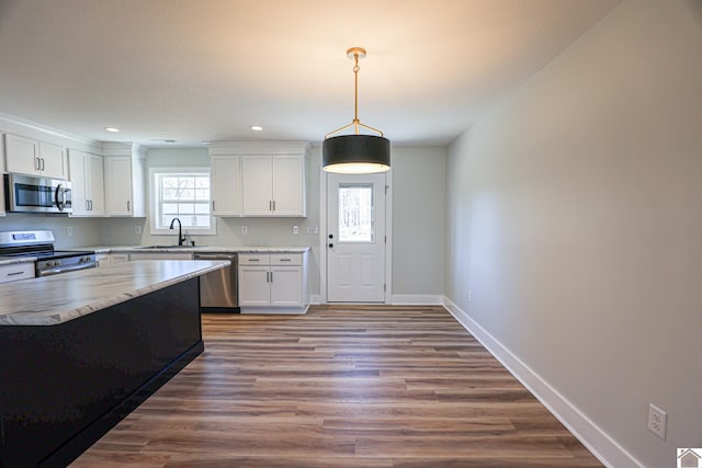 kitchen featuring a healthy amount of sunlight, stainless steel appliances, hanging light fixtures, and white cabinets