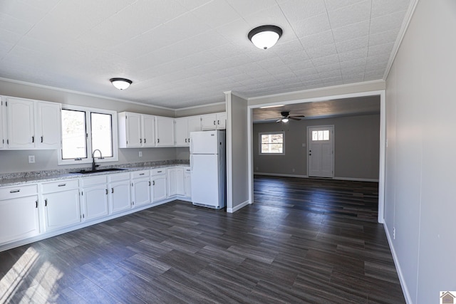 kitchen with sink, ornamental molding, white fridge, light stone countertops, and white cabinets