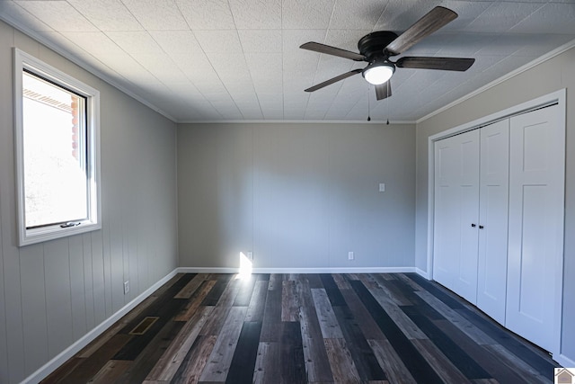 unfurnished bedroom with ornamental molding, dark wood-type flooring, ceiling fan, and a closet