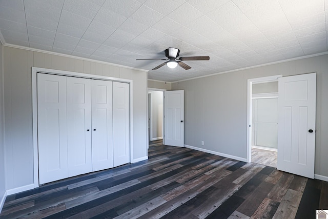 unfurnished bedroom featuring dark wood-type flooring, ceiling fan, ornamental molding, and a closet