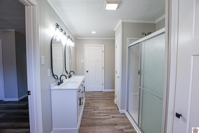 bathroom featuring a shower with door, vanity, ornamental molding, and hardwood / wood-style floors