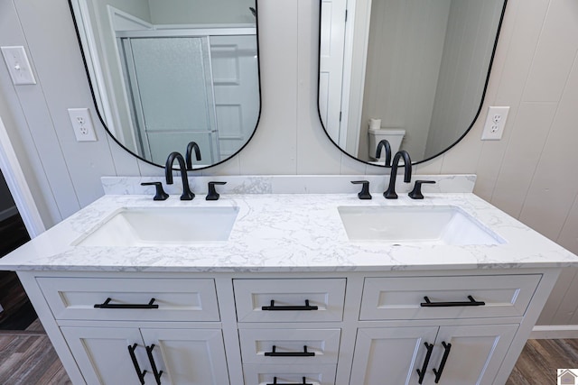 bathroom featuring wood-type flooring, toilet, an enclosed shower, and vanity