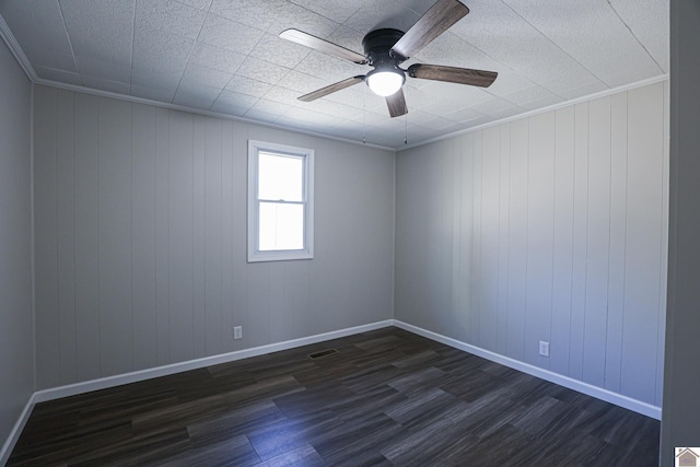 empty room with crown molding, dark wood-type flooring, and ceiling fan