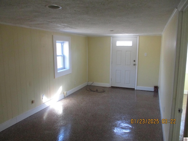 foyer with wooden walls and a textured ceiling