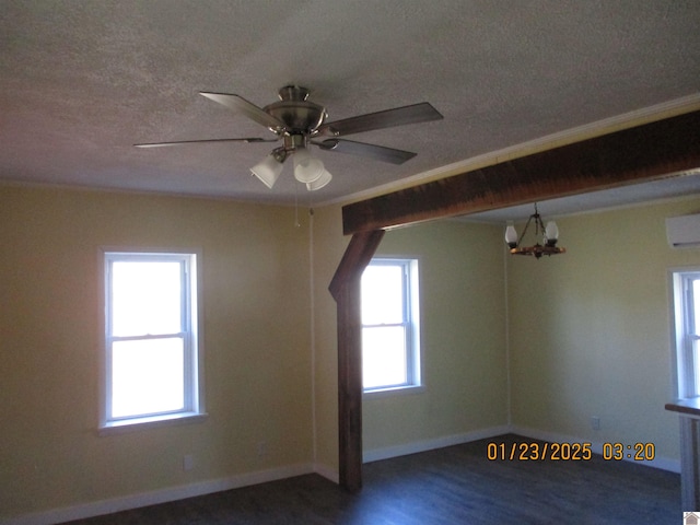 additional living space featuring an AC wall unit, dark wood-type flooring, a wealth of natural light, and a textured ceiling