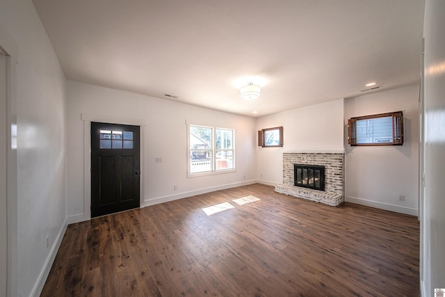 unfurnished living room with a brick fireplace and dark hardwood / wood-style flooring