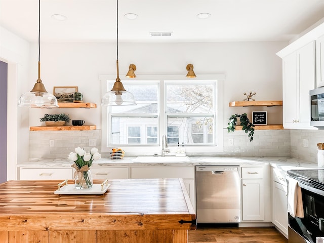 kitchen featuring stainless steel appliances, hanging light fixtures, sink, and white cabinets