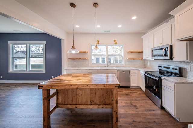 kitchen featuring pendant lighting, appliances with stainless steel finishes, white cabinetry, dark hardwood / wood-style floors, and tasteful backsplash