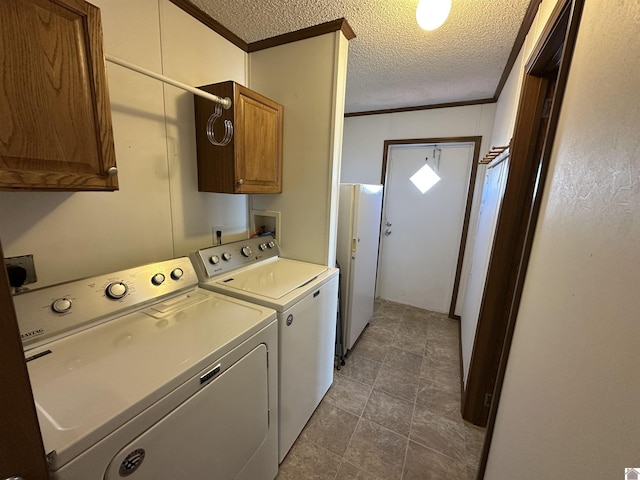 laundry room with washer and clothes dryer, ornamental molding, cabinets, and a textured ceiling