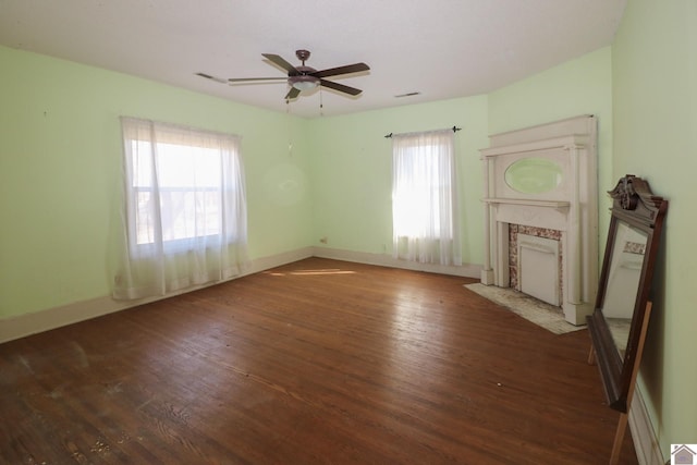 unfurnished living room with dark wood-type flooring, a healthy amount of sunlight, and a premium fireplace